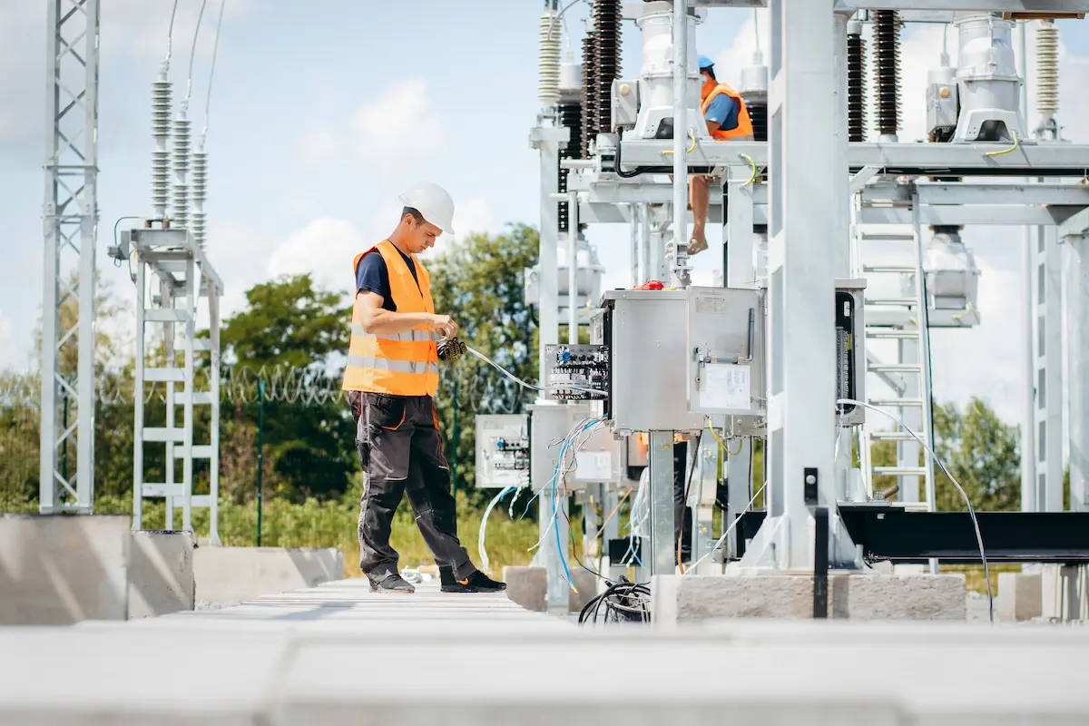 Licensed electrician in protective helmet working on high voltage power lines