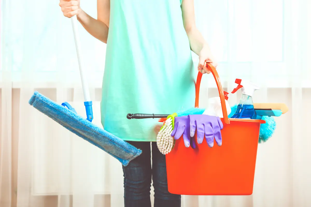 Professional house cleaner with a mop and cleaning products ready to service a residential home