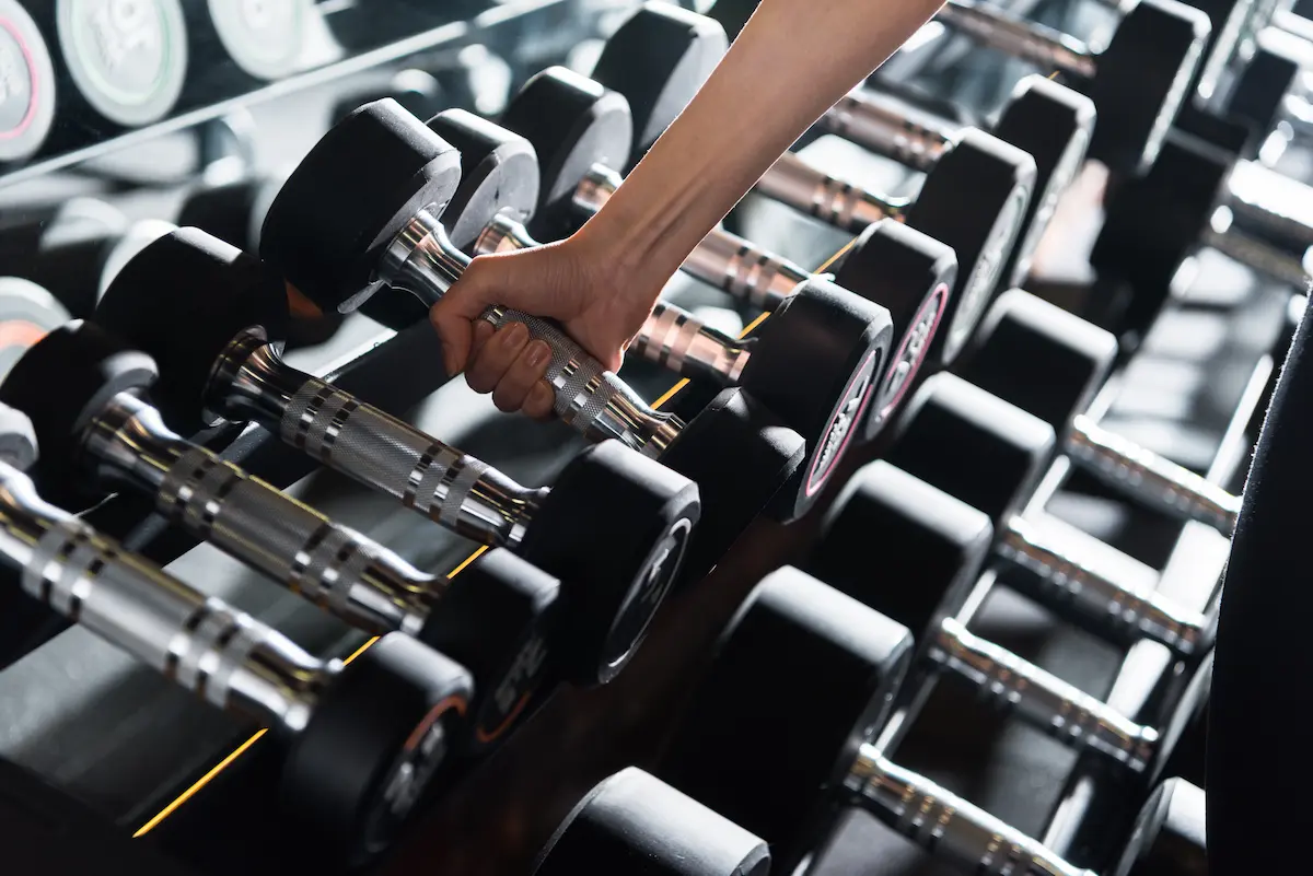 Athletic woman lifting a heavy dumbbell during a strength training session at a gym