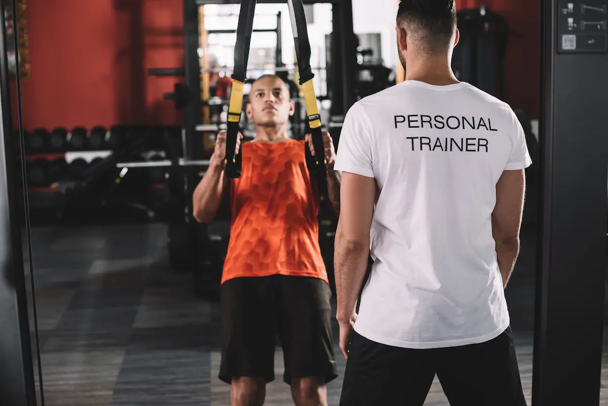 Personal trainer coaching a client through a strength training exercise at a gym