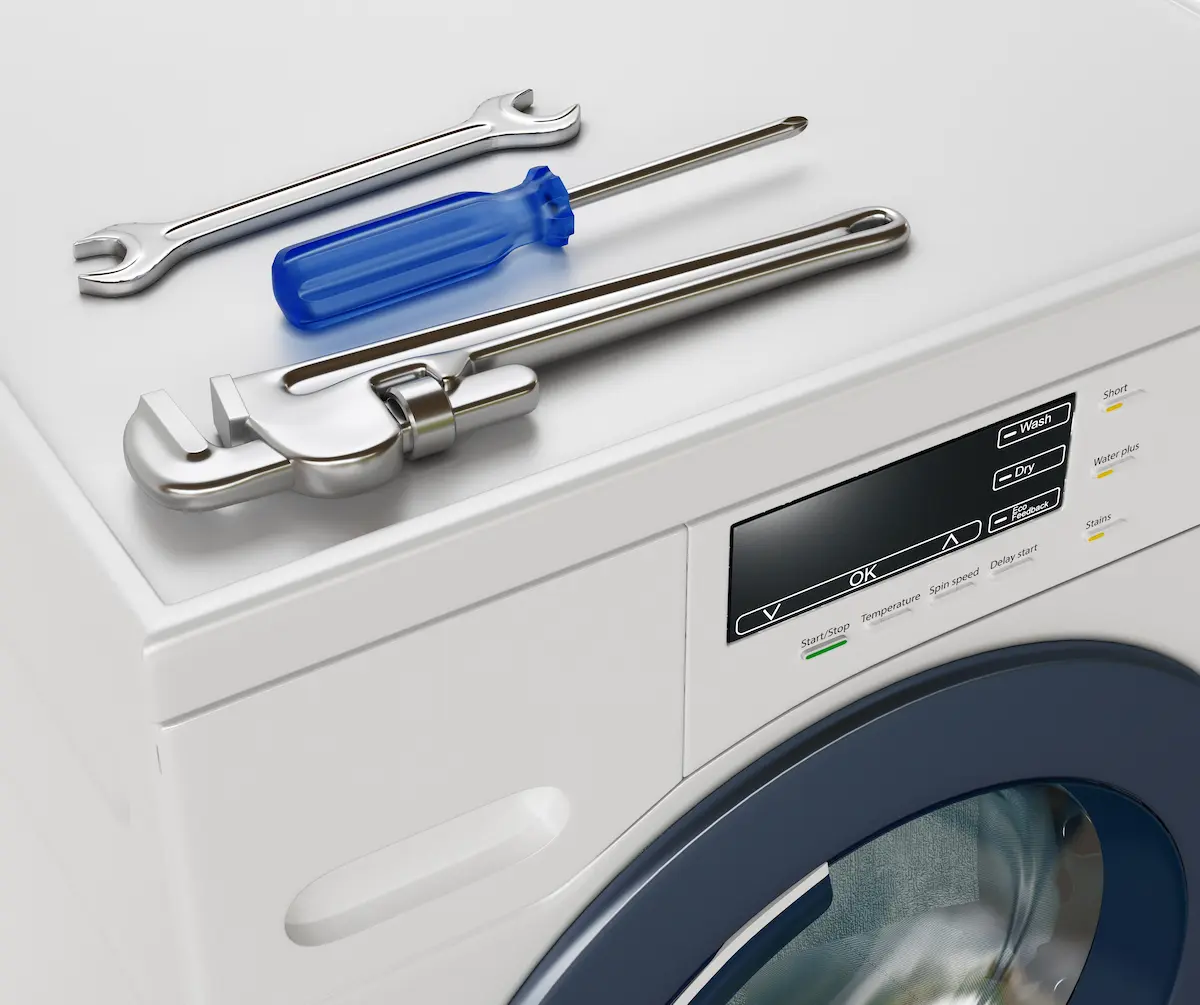 Appliance repair technician working on a washing machine in a home setting