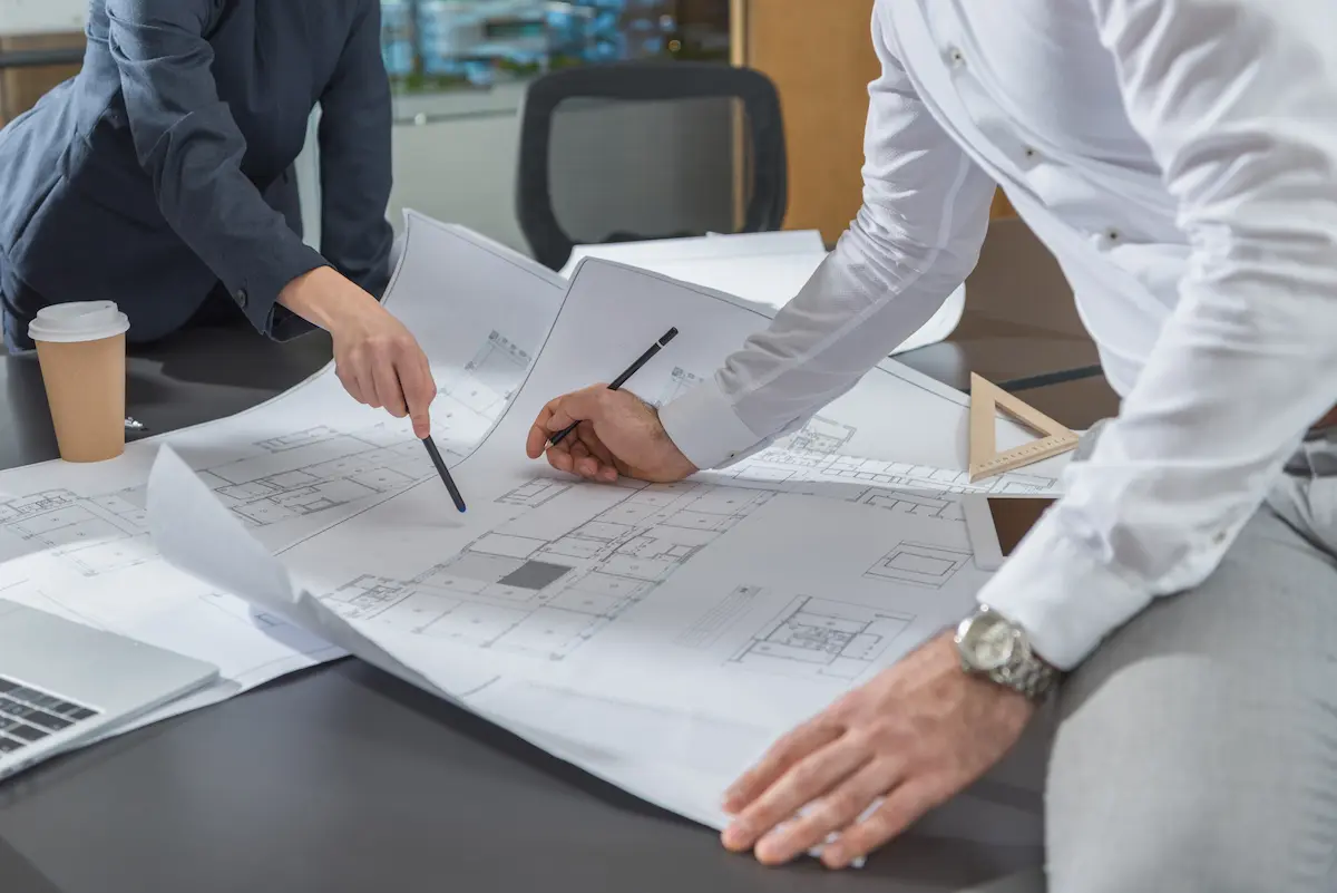 Two architects collaborating over building plans and blueprints at a professional office desk