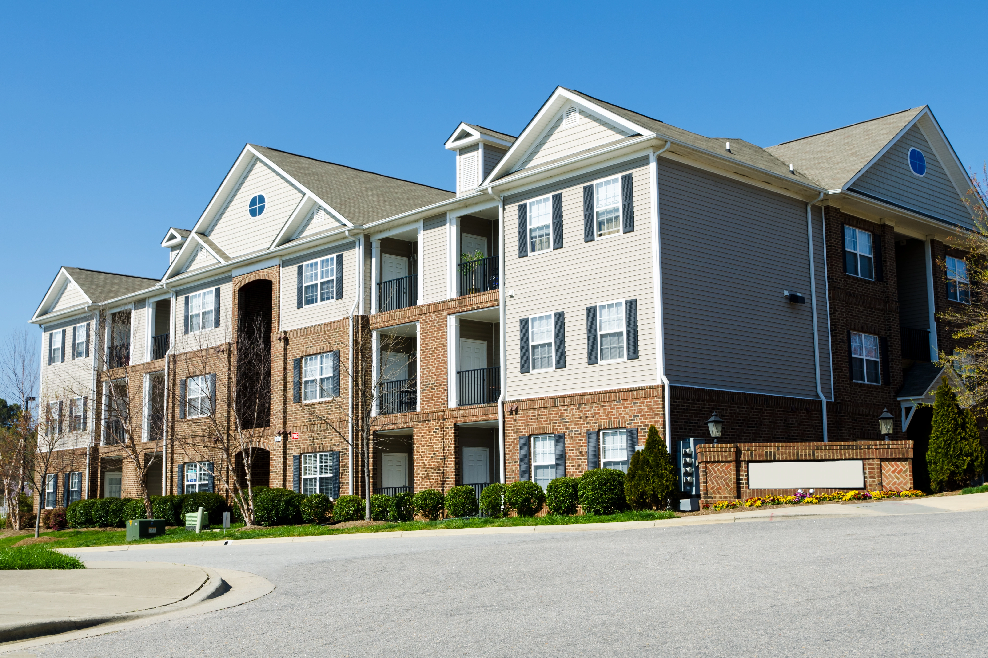 Modern multi-story apartment building complex with landscaping and resident parking