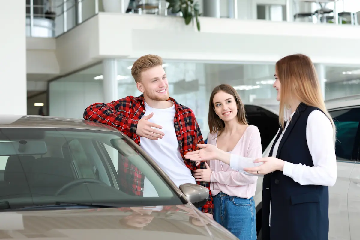 Couple choosing a new car together at an auto dealership showroom