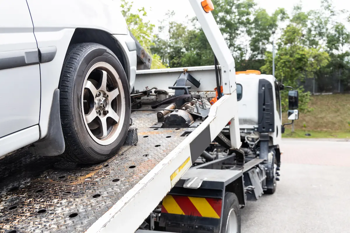 Cable attached to a broken down car being pulled onto a tow truck during a roadside emergency
