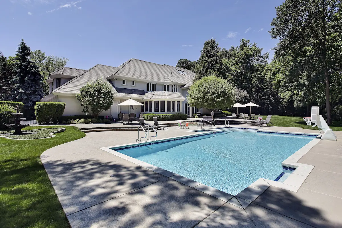 Completed residential swimming pool with surrounding deck and landscaping in a backyard setting