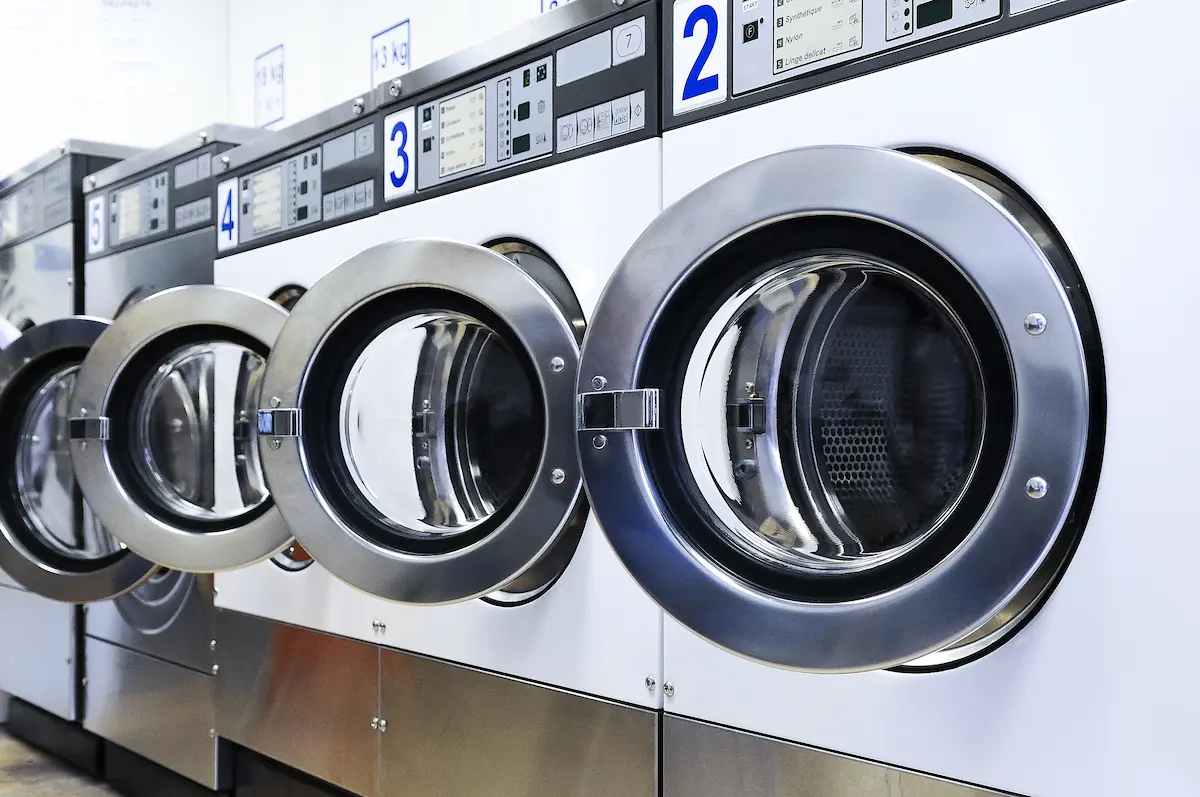 Clean and modern laundromat interior with rows of washers and dryers available for customer use