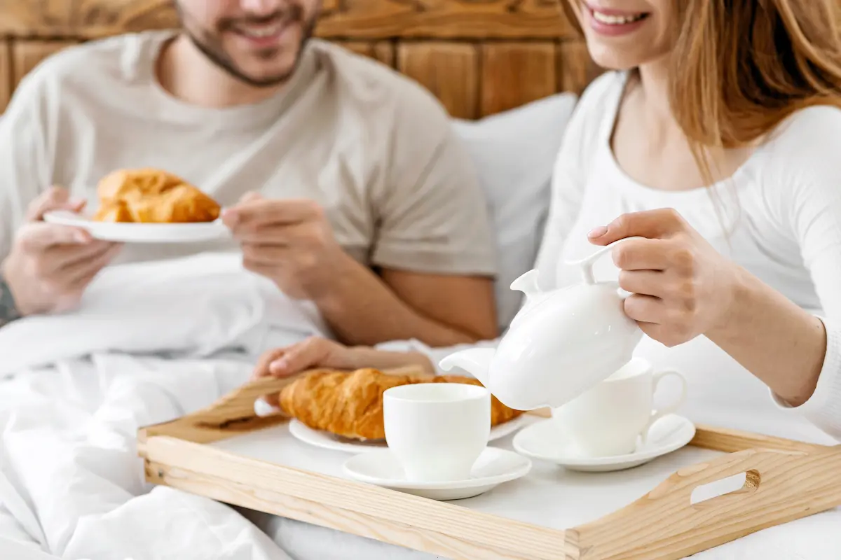 Romantic breakfast in bed at a cozy inn with a happy couple enjoying a honeymoon stay