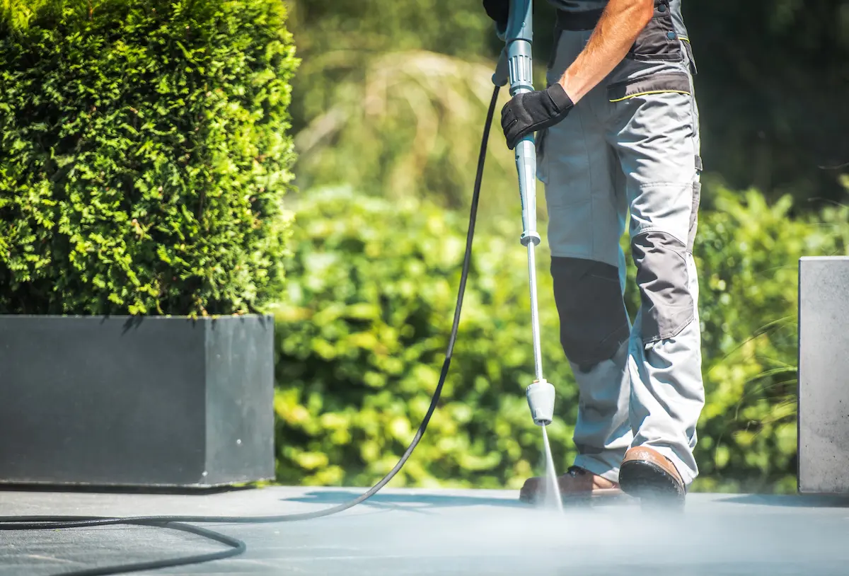 Professional pressure washing contractor cleaning a concrete patio surface with a high-pressure washer