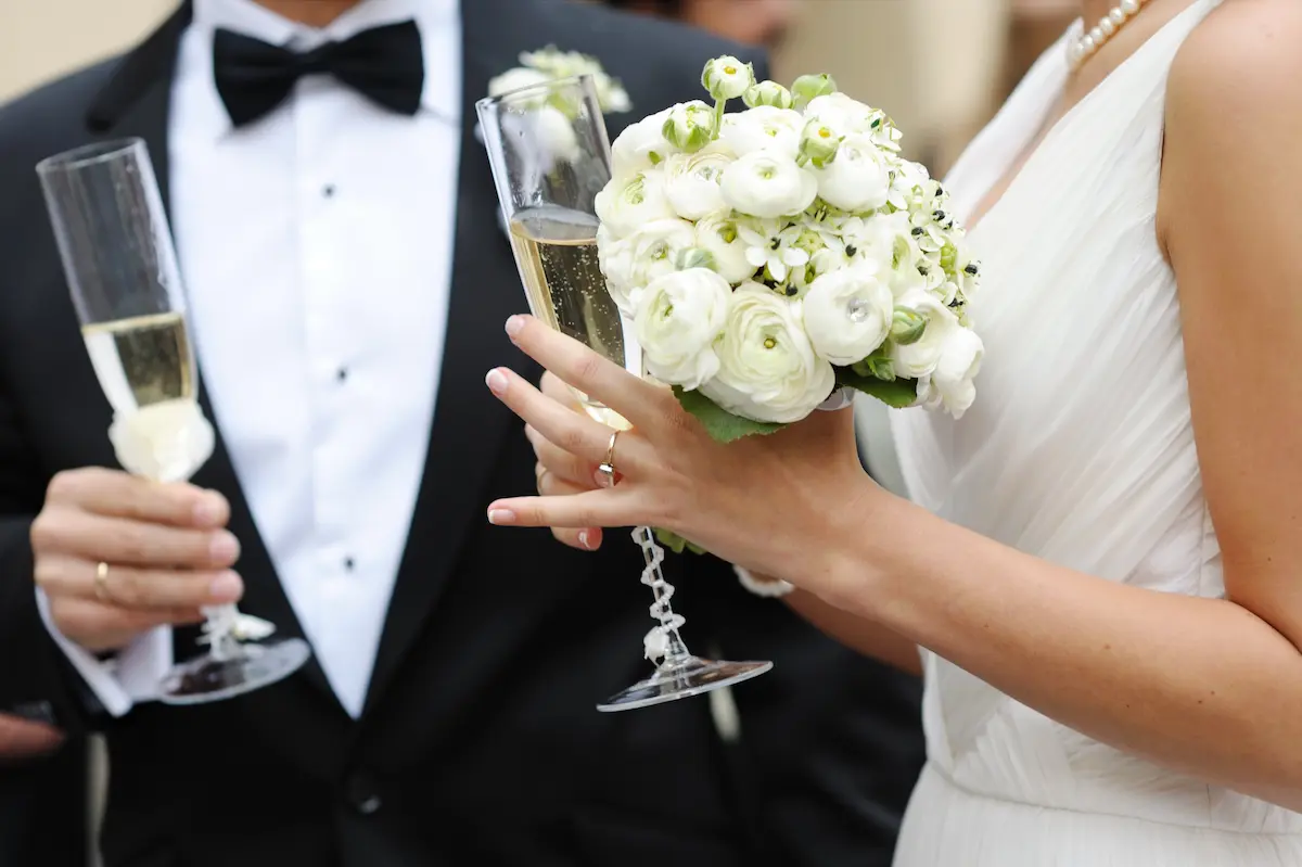 Bride and groom celebrating their wedding ceremony with champagne glasses in a romantic outdoor setting