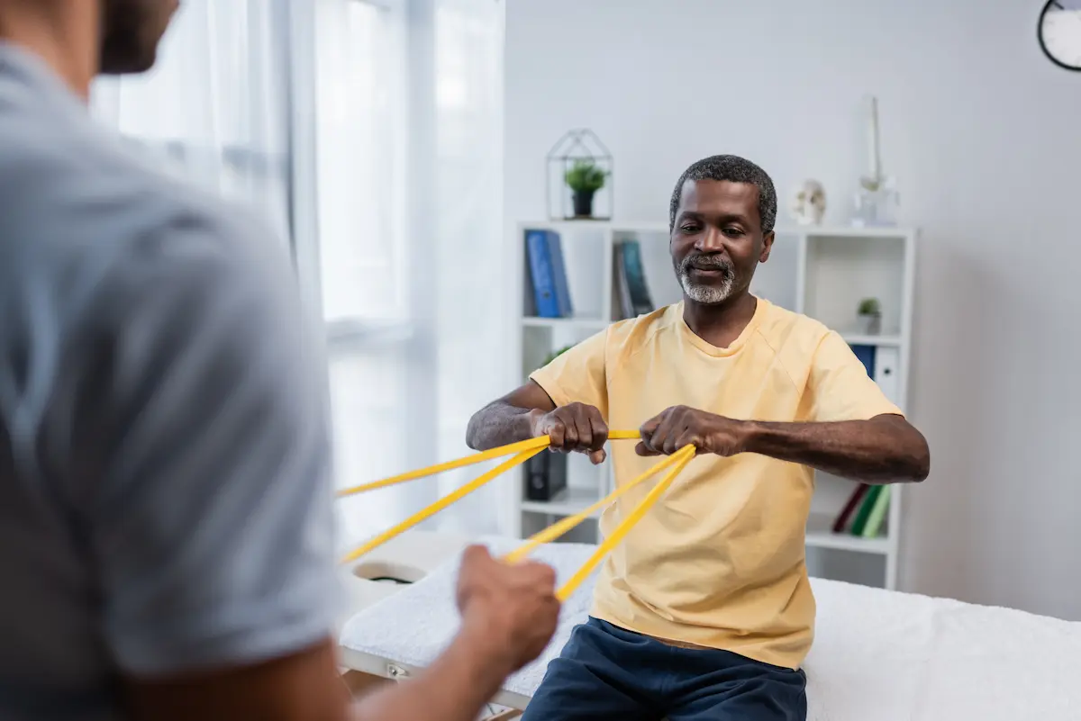 Physical therapist guiding a patient through rehabilitation exercises using resistance bands in a clinical setting