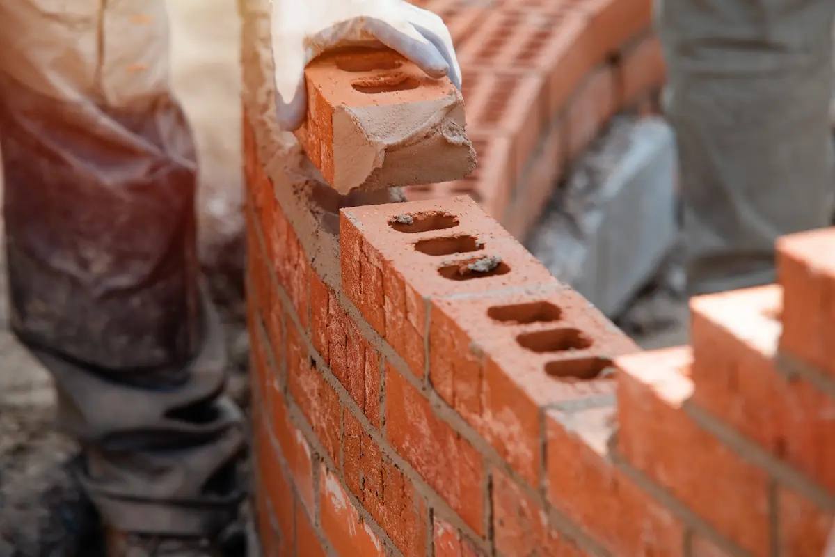 Skilled bricklayer working on a curved masonry wall demonstrating expert craftsmanship in brick and stone construction