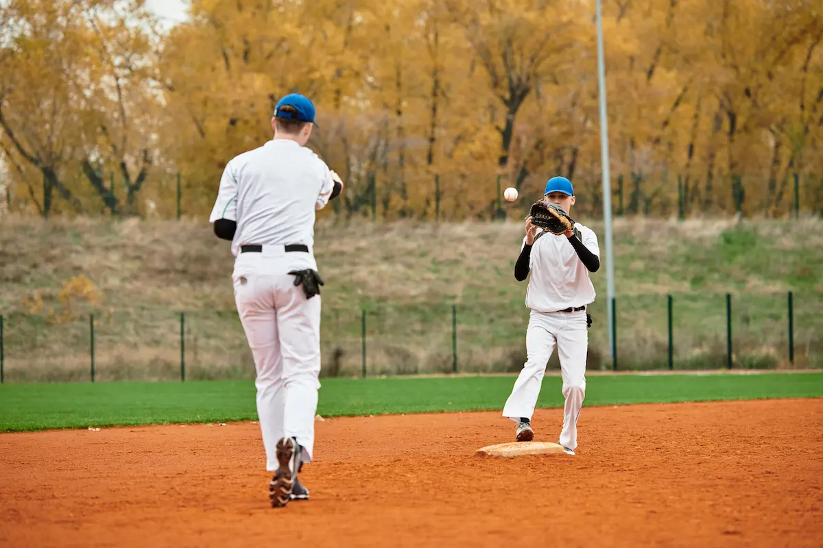 Youth baseball players practicing on a vibrant field surrounded by trees in an energetic youth baseball club environment