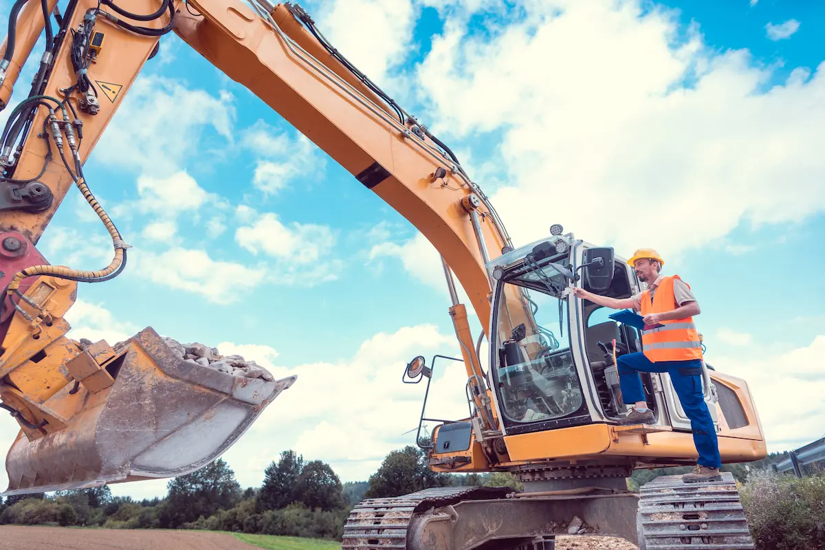 Construction worker operating an excavator on a job site planning the earthmoving work for an excavation contractor project