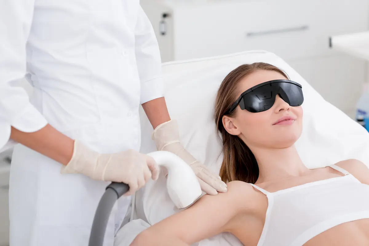 Woman receiving a laser hair removal procedure on her arm at a professional aesthetic clinic