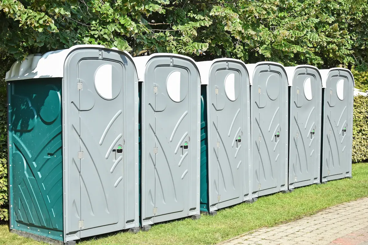 Portable toilets lined up on a street representing professional portable sanitation rental services for construction sites and outdoor events