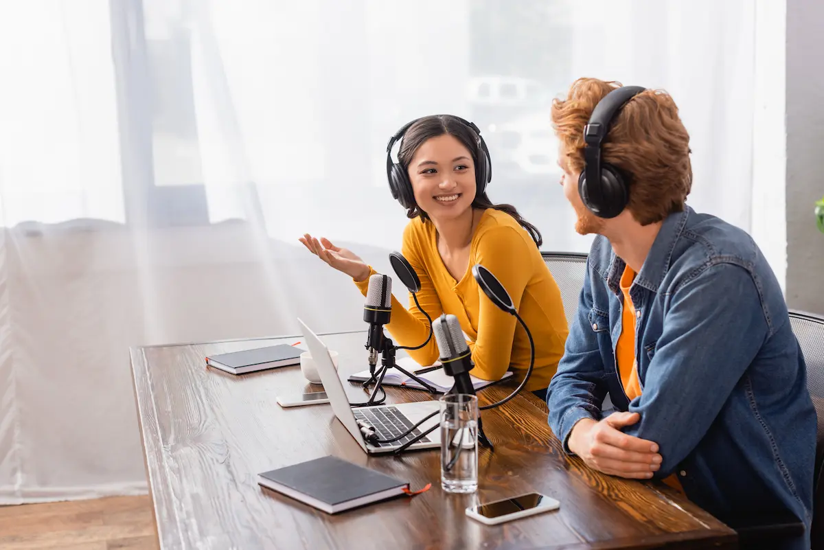 Podcast host with wireless headphones gesturing while recording in a professional radio studio representing a credible and well-produced podcast