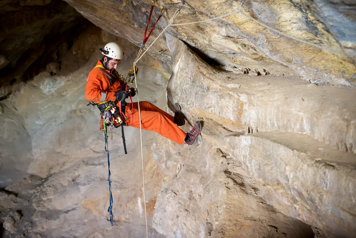 Search and rescue specialist performing rope maneuvers in a cave representing the technical skill and mission commitment of a professional search and rescue organization