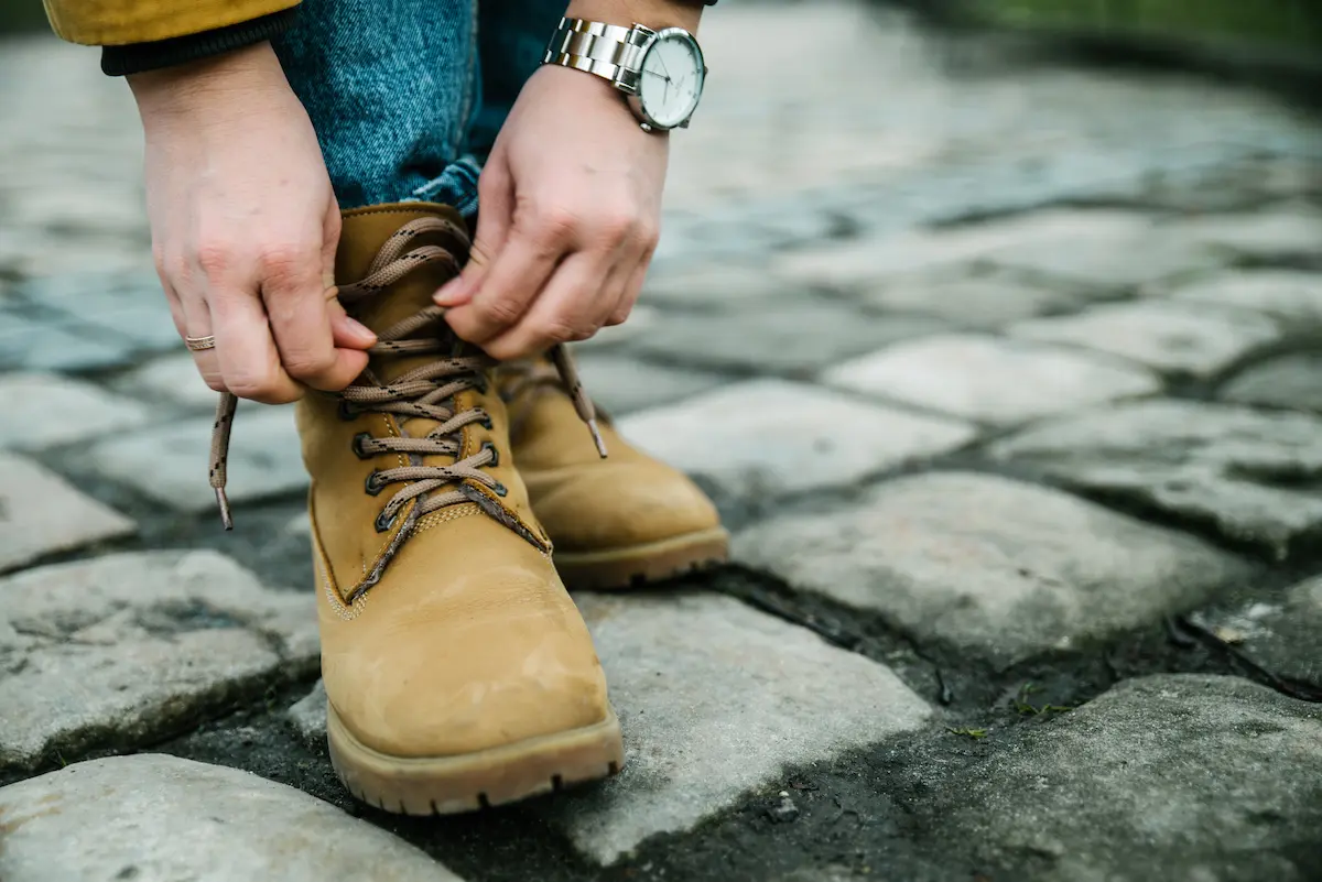 Young woman lacing up boots on an autumn day representing the care and quality craftsmanship that a skilled shoe and boot repair shop brings to every pair of footwear