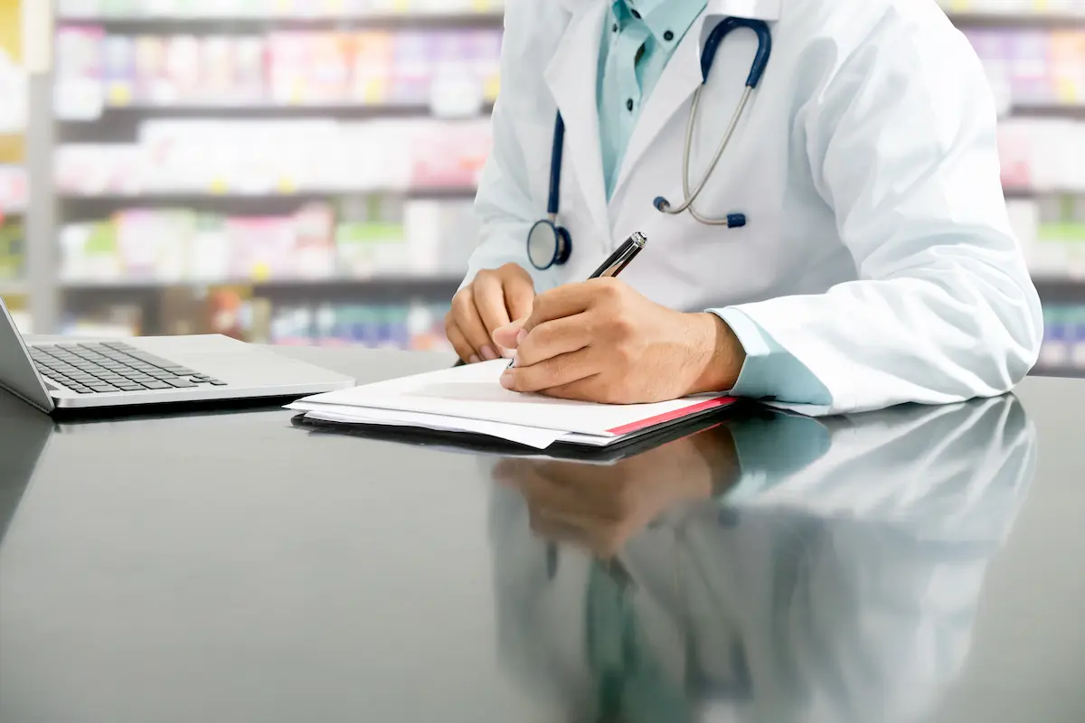 Pharmacist reviewing patient documents at a pharmacy counter representing the attentive and personalized care that an independent pharmacy provides to every patient