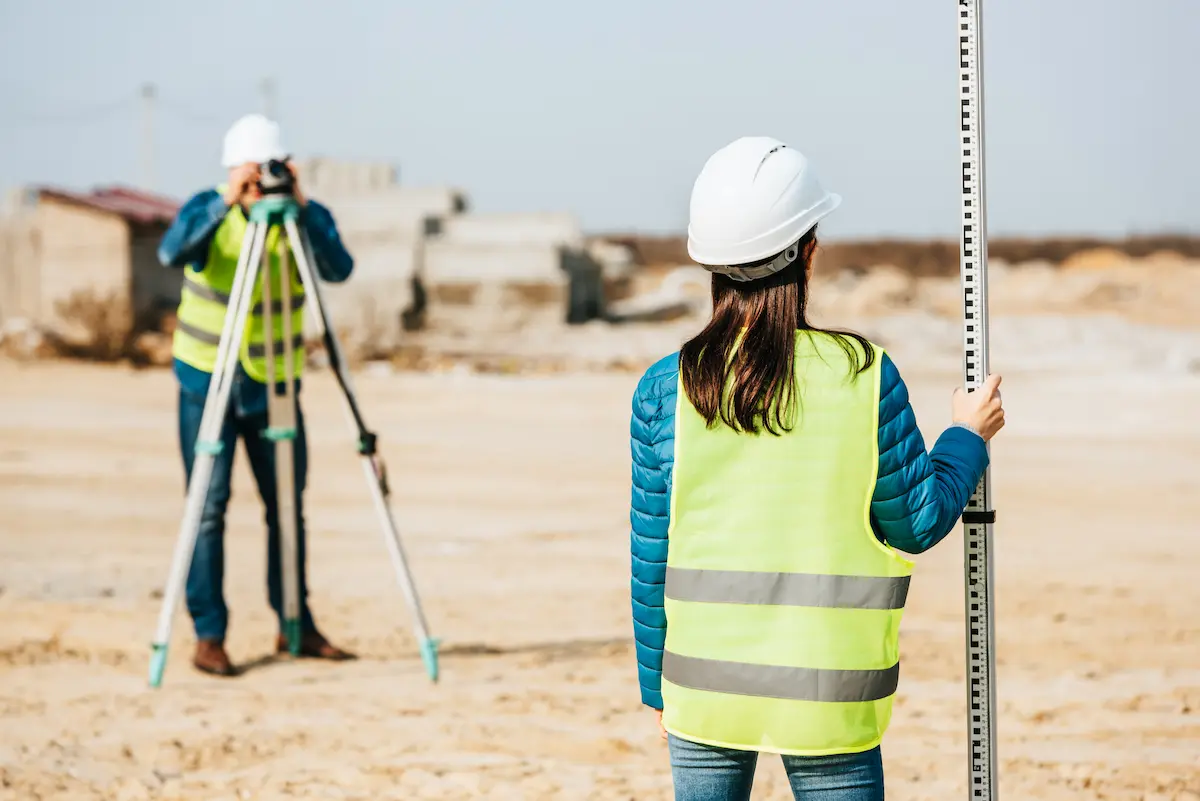 Land surveyors using professional equipment in the field representing the precise boundary determination and topographic survey work performed by a licensed land surveying firm
