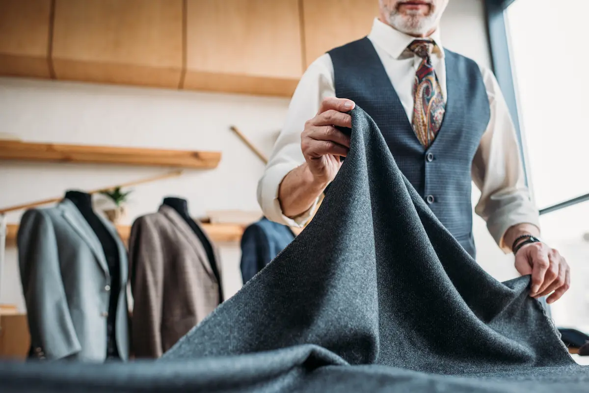 Skilled tailor working with grey fabric at a sewing workshop representing the precise and expert tailoring and alterations craftsmanship that an experienced local tailor provides