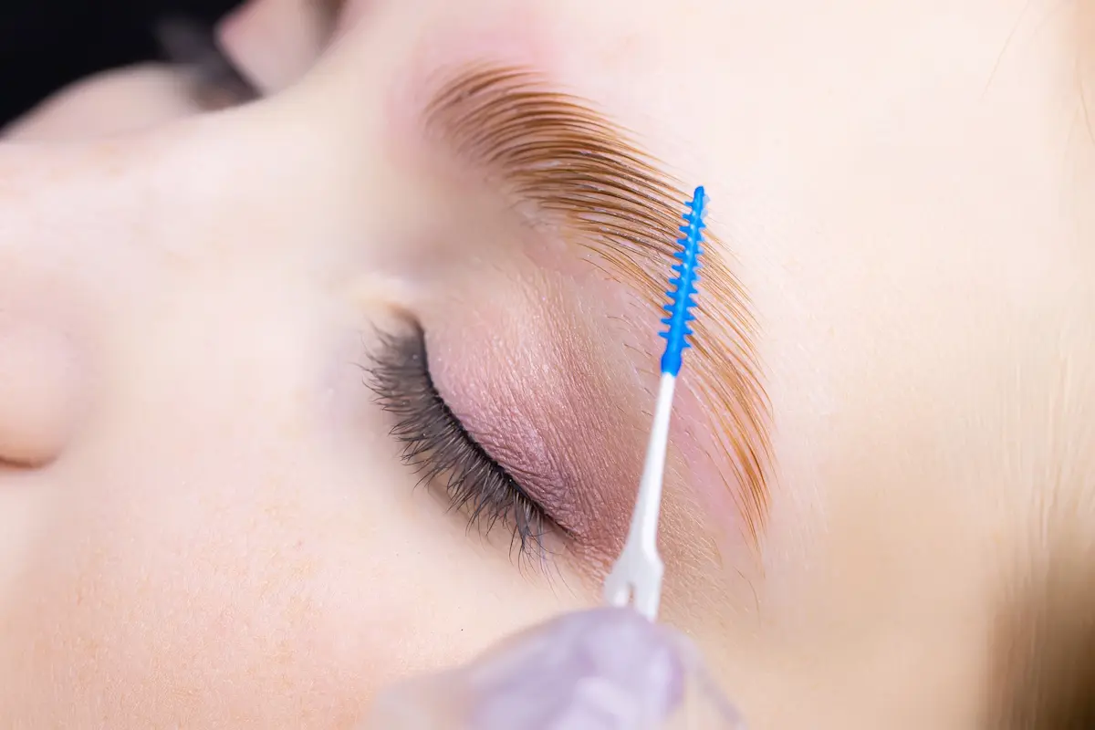 Beauty professional performing an eyebrow lamination procedure representing the precise and skilled lash and brow artistry that a quality lash and brow studio provides for its clients