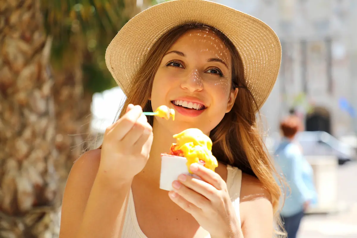 A young woman enjoying a colorful Italian ice representing the refreshing and festive frozen treat experience that a mobile Italian ice cart brings to weddings, parties, and events