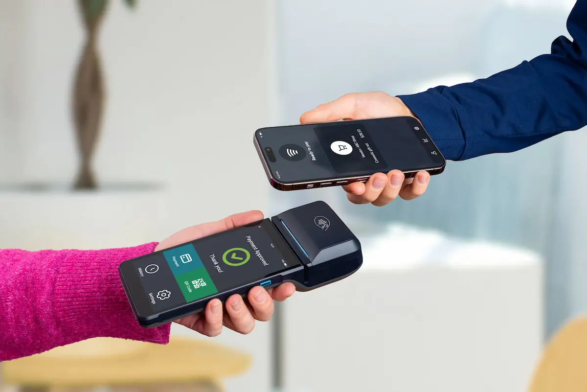 A smartphone and POS terminal completing a contactless payment showing a modern merchant interface representing the seamless and efficient payment processing solutions that a quality merchant services provider delivers