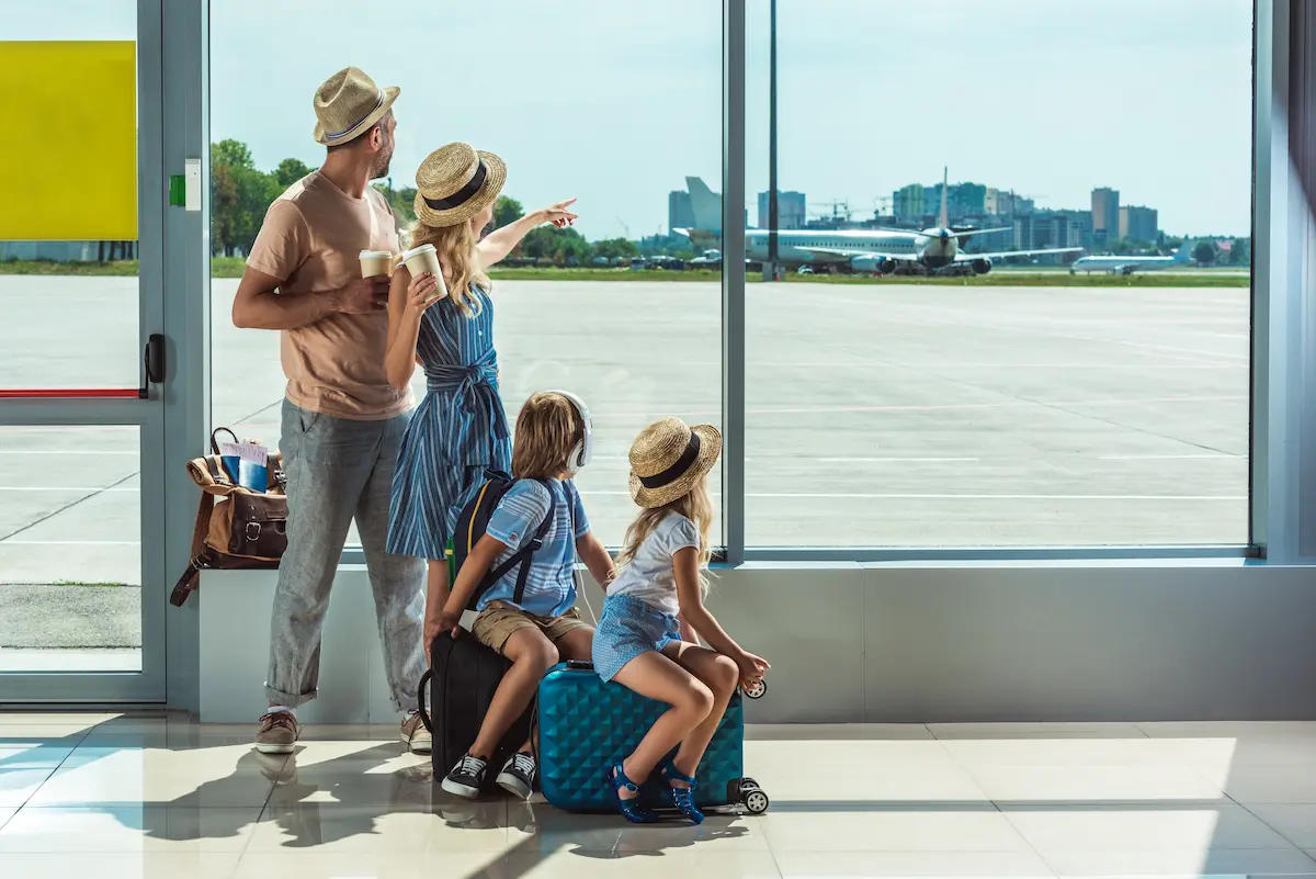 A family looking out the window in an airport representing the excitement and anticipation of travel that a skilled travel agency helps clients plan and experience to the fullest