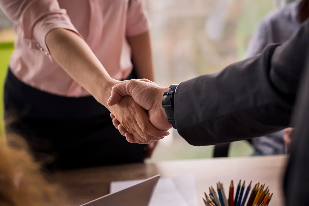 A male and female professional shaking hands on a business deal representing the successful real estate closing that a professional title company delivers for buyers, sellers, agents, and lenders