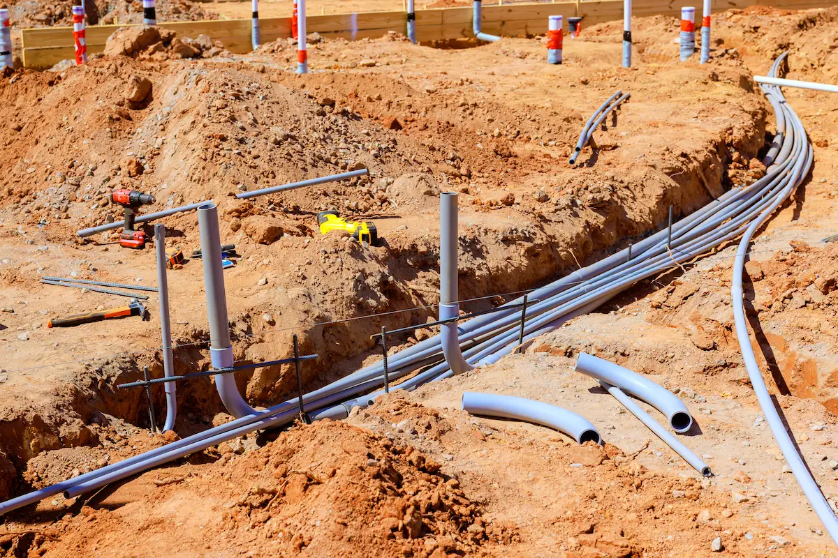 Workers installing electrical piping at a construction site showcasing groundwork utilities representing the critical subsurface infrastructure that underground utility locators identify and map to keep excavation crews safe and projects on schedule