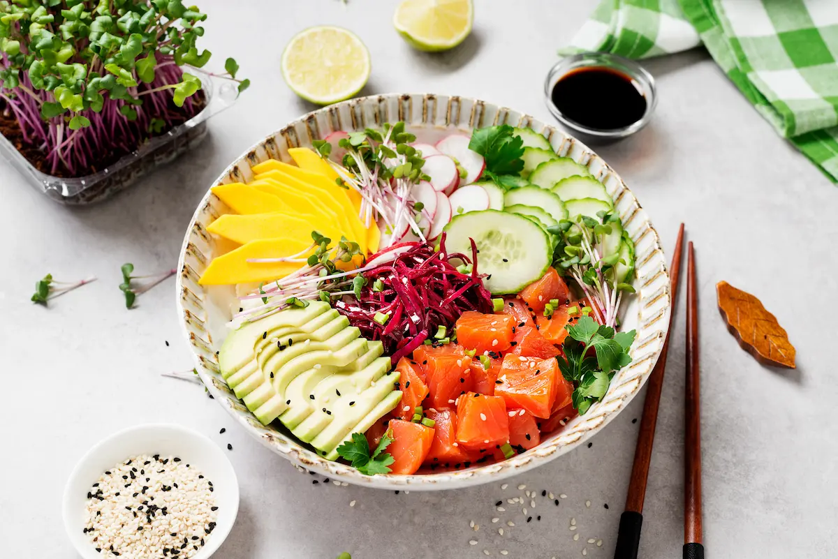 A beautiful poke bowl featuring fresh marinated salmon with variegated vegetables, green onions, and microgreens representing the quality fresh ingredients and vibrant customization that a great poke restaurant offers every diner