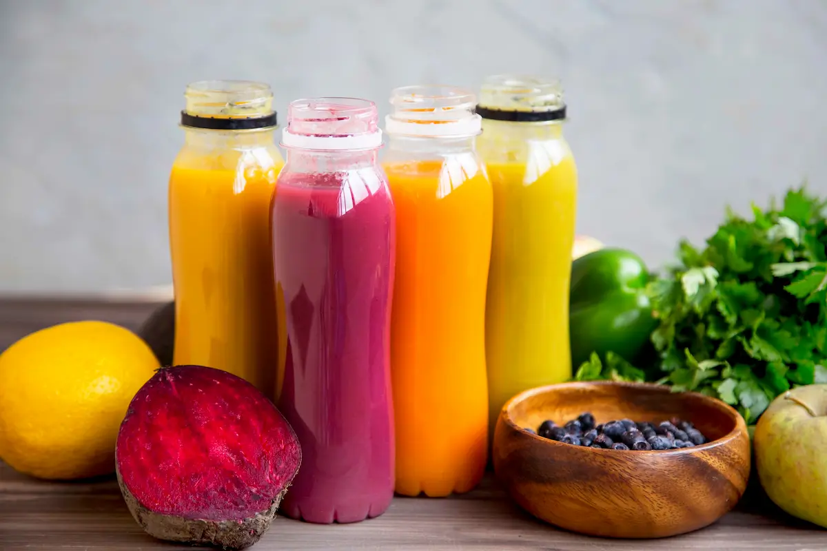 A colorful collection of fresh organic smoothies in bottles made from fruits and vegetables representing the vibrant health-forward blends and fresh ingredients that a quality juice bar and smoothie shop delivers every day