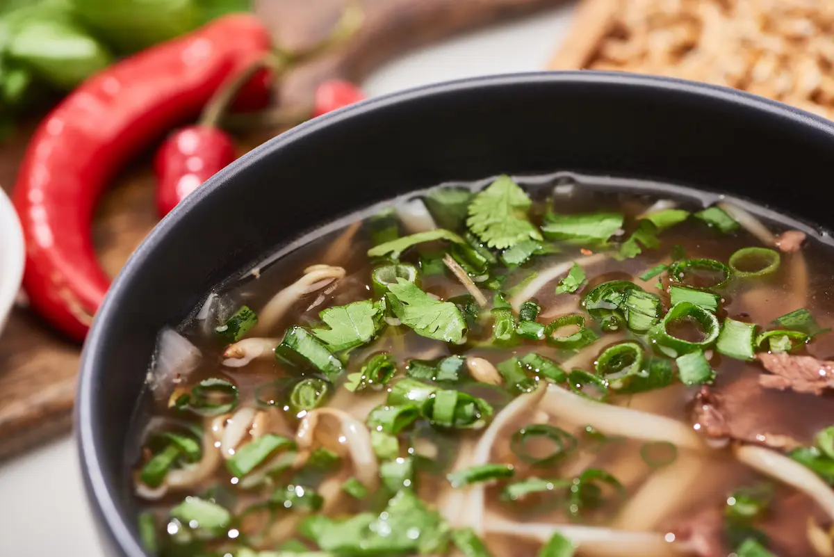 A close view of a steaming bowl of pho noodles with meat, fresh cilantro, and green onion representing the rich long-simmered broth, fresh ingredients, and authentic Vietnamese culinary tradition that a great pho restaurant delivers in every bowl