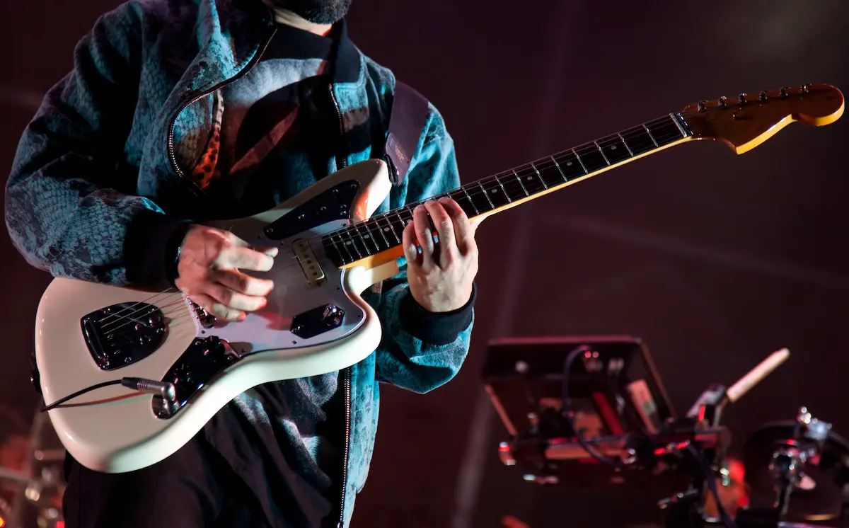 A guitarist performing on stage with dramatic lighting representing the energy, stage presence, and live performance power that a great rock band brings to every venue show, private event, and festival appearance