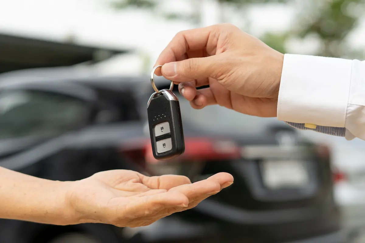 A customer receiving car keys from a car rental company representative while signing a rental contract representing the professional service, transparent process, and reliable vehicle handoff that a great local car rental company delivers to every renter