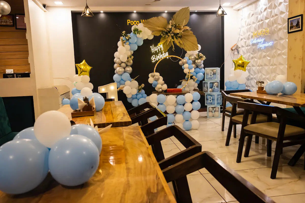A beautiful first birthday party balloon decoration setup with white and blue balloons arranged in a stunning arch and column display representing the professional balloon decor artistry and creative event decoration that a talented balloon decor business delivers to every birthday party, wedding, and special event