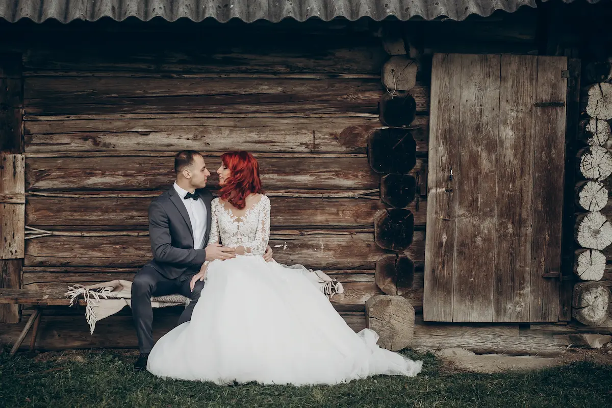 A wedding couple sitting together on a bench at a rustic venue surrounded by natural beauty representing the intimate, romantic, and unforgettable wedding day atmosphere that a professional rustic wedding venue creates for every couple who chooses to celebrate their love in a setting that feels genuine, warm, and beautifully imperfect
