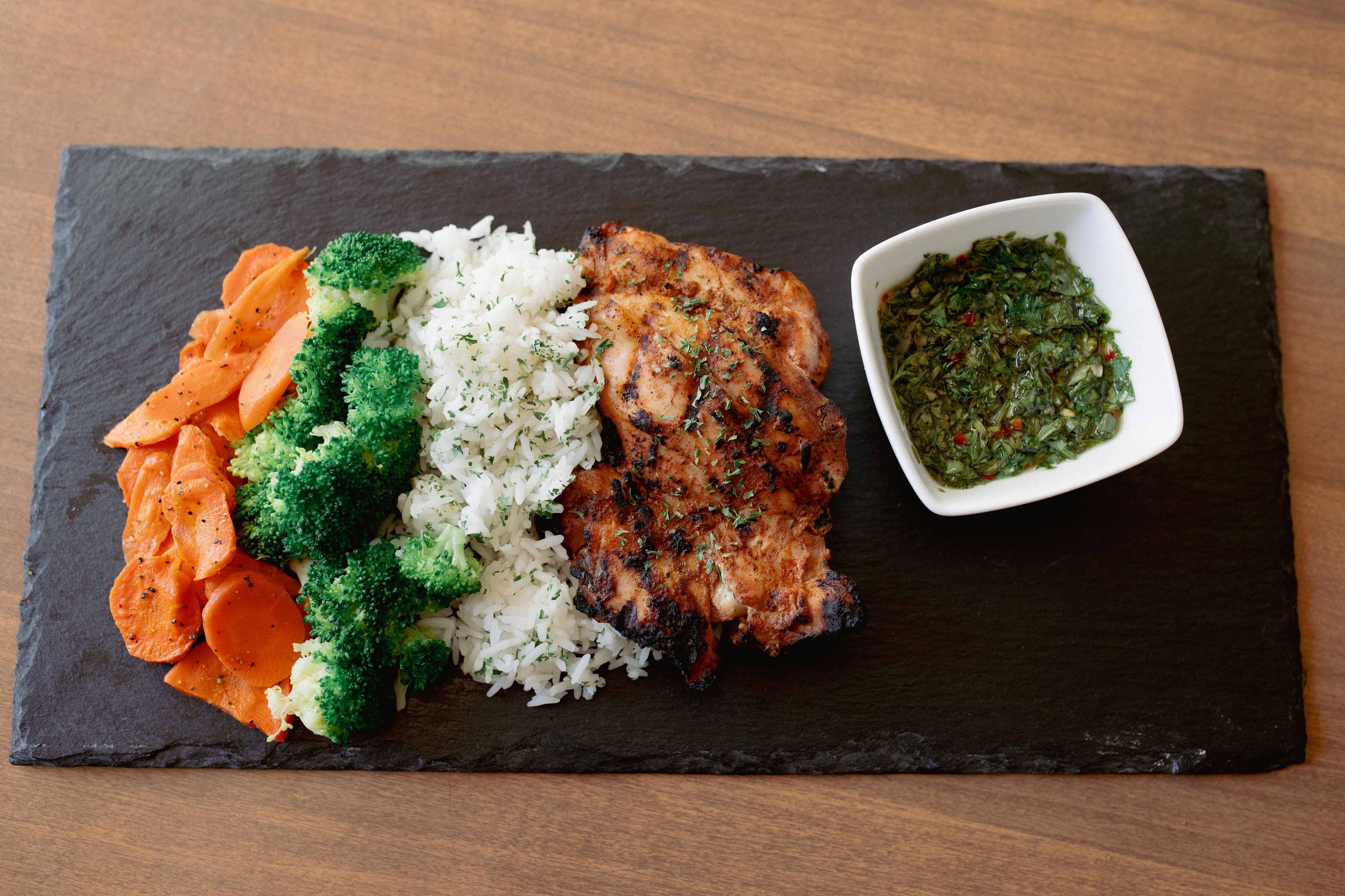 Chimichurri bowl with grilled chicken, rice, broccoli, carrots and green chimichurri sauce