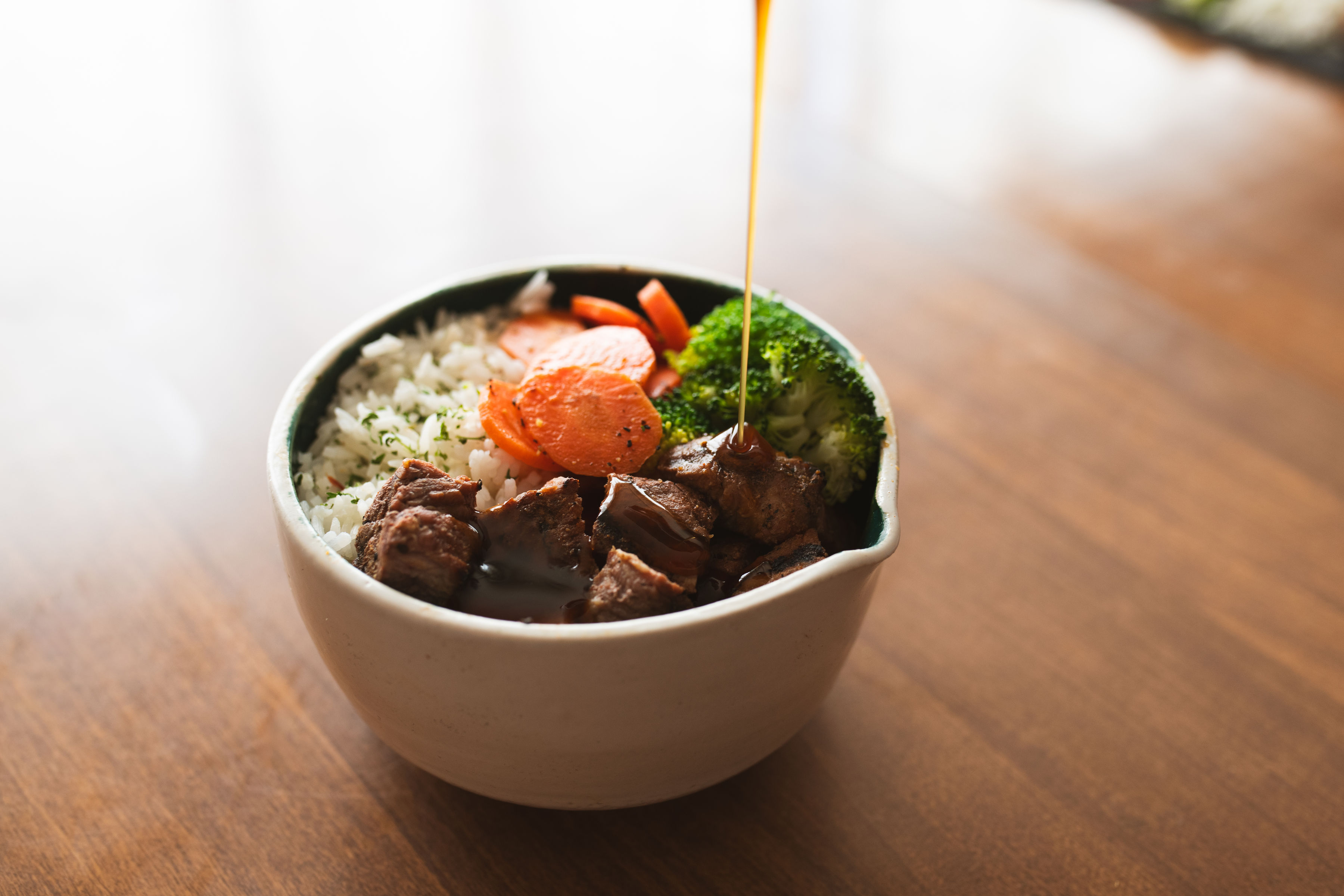 Ginger teriyaki bowl with glossy glazed steak over rice, broccoli and carrots