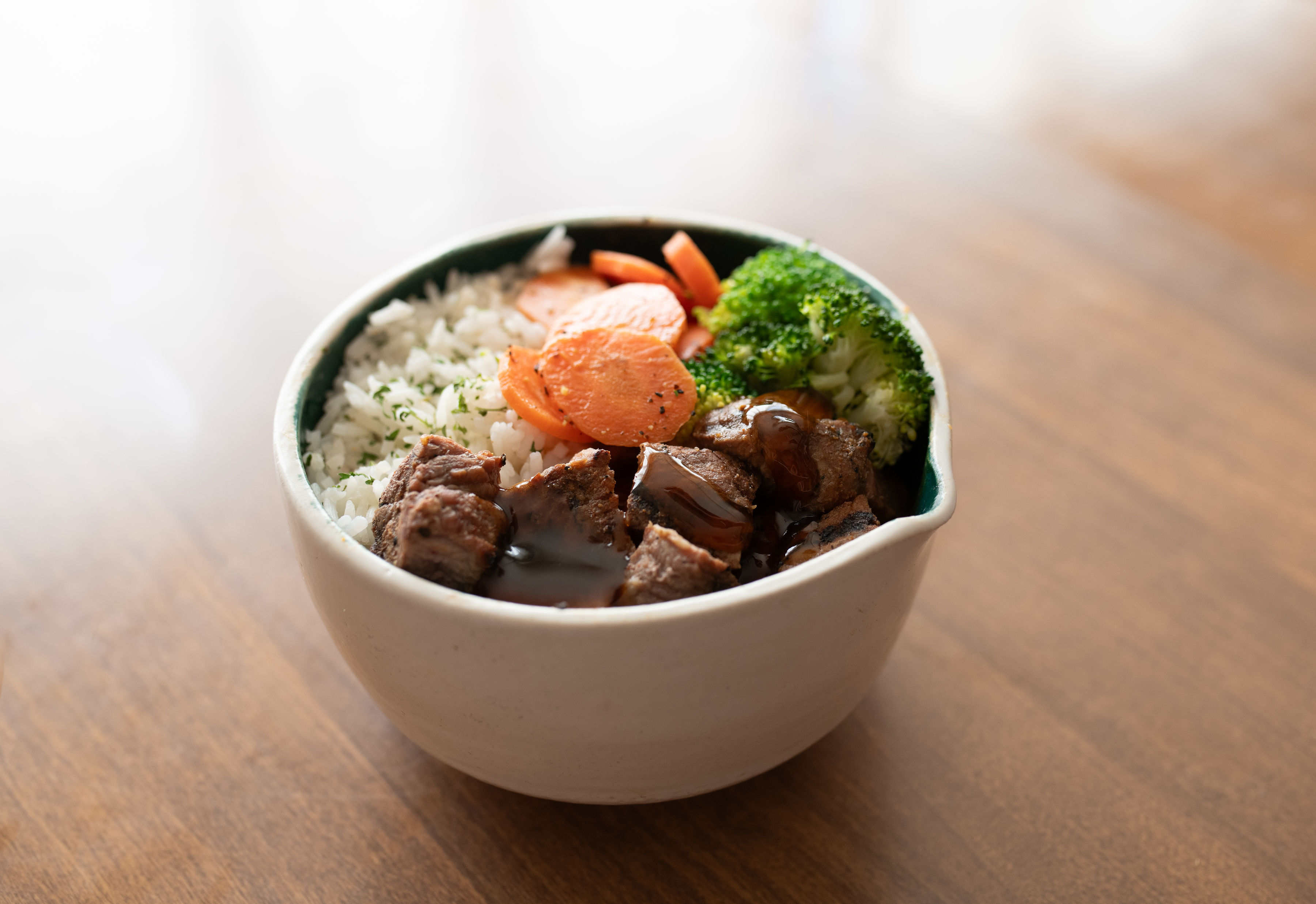 Sweet onion BBQ bowl with glazed steak over rice with broccoli and carrots