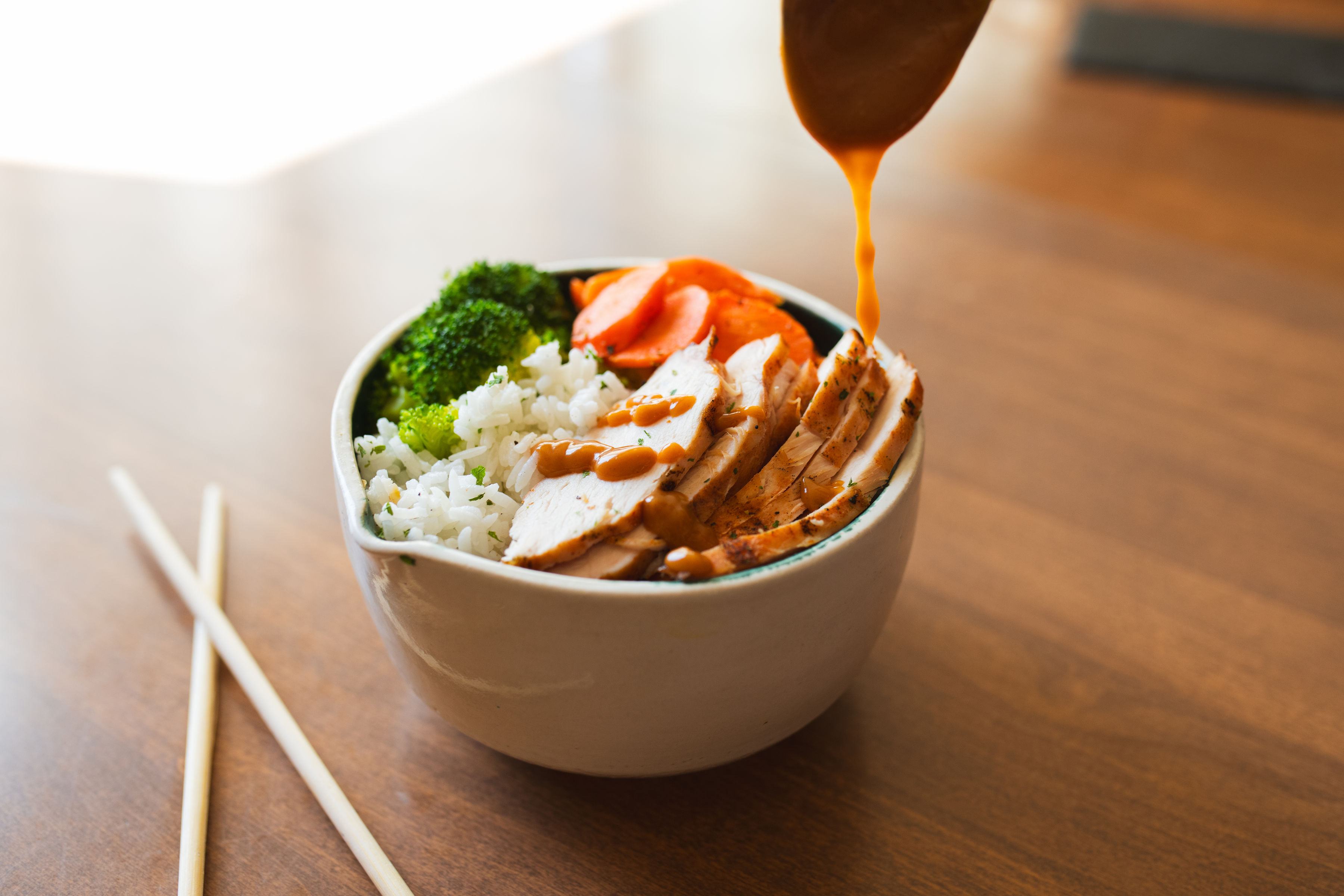 A fresh Last Bite bowl of glazed chicken over jasmine rice with broccoli and carrots