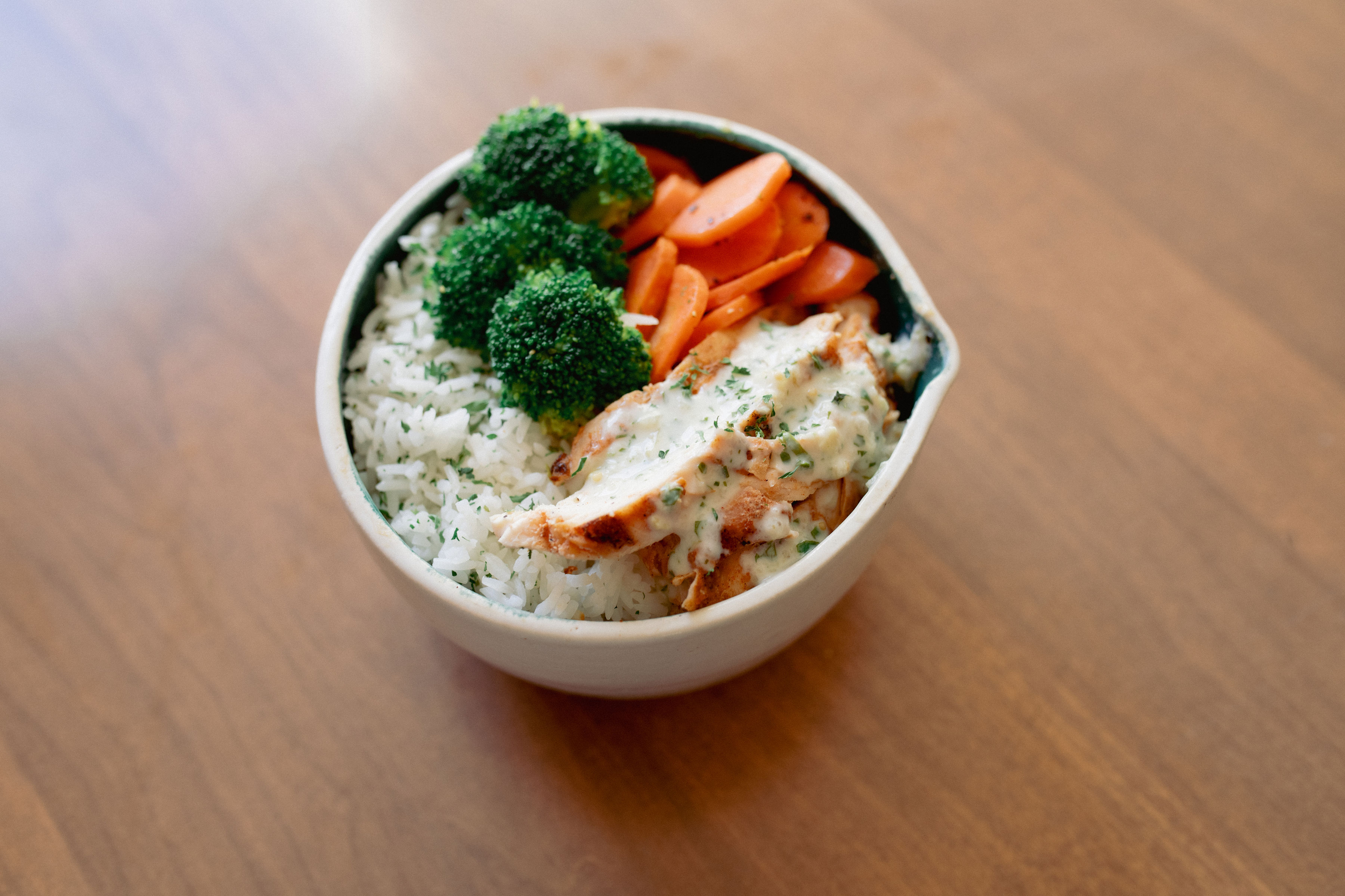 Tuscan bowl with chicken in creamy sun-dried tomato sauce over rice with broccoli and carrots